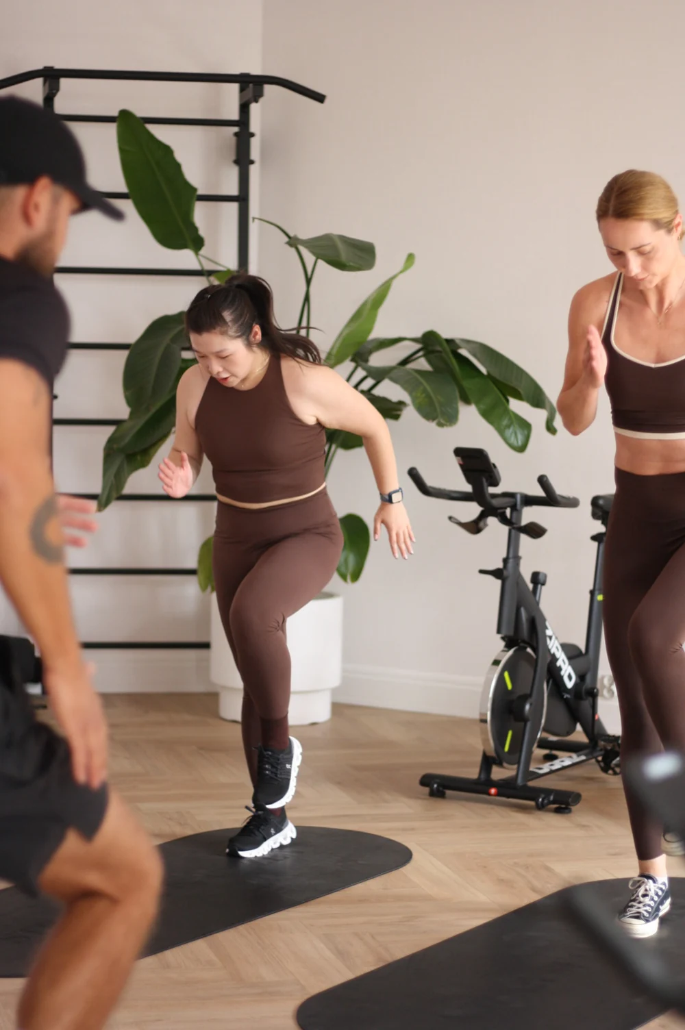 Uczestniczki zajęć cardio podczas ćwiczeń na macie z prowadzącym